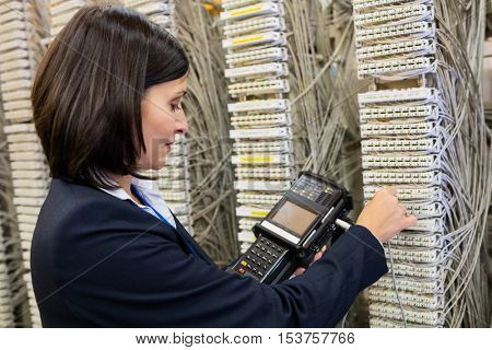 Technician using digital cable analyzer in server room