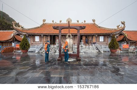 Sa Pa Vietnam - September 18 2016: Temple on top of Fansipan Legend mountain on cloudy with rain staff ringing golden bell before sunset.