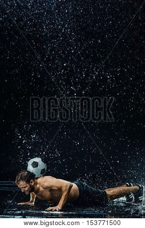 Water drops around football player on black background