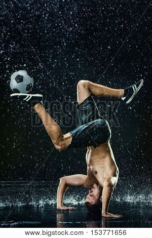 Water drops around football player on black background