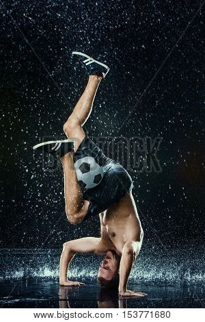 Water drops around football player on black background