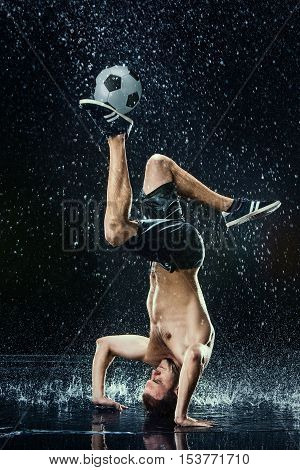 Water drops around football player on black background