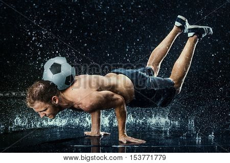 Water drops around football player on black background