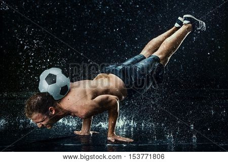 Water drops around football player on black background