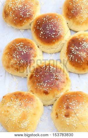 Freshly cooked, home-made burger buns on an aluminium sheet covered with greaseproof paper.