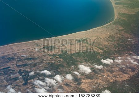 aeral shot of a small town at the sea ocean coast and green fiels around