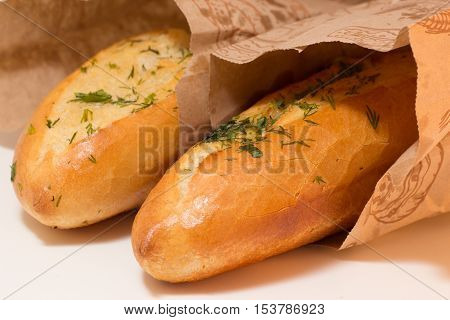 two baguettes covered with greens potherbs herbs in paper bags closeup shot