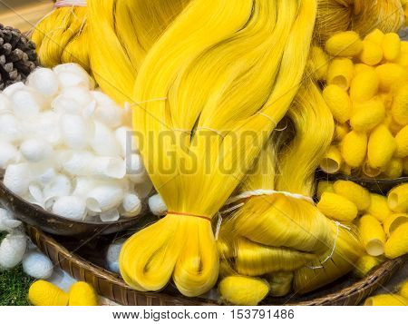 Silk cocoons and raw silk threads in basket.