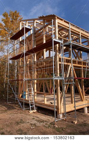 Metal scaffolding around the unfinished house. Construction of ecological house. Wooden frame of house under construction.Framed New Construction of a House. Timber house in building process