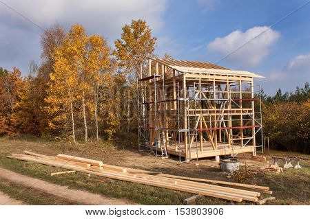 Metal scaffolding around the unfinished house. Construction of ecological house. Wooden frame of house under construction.Framed New Construction of a House. Timber house in building process