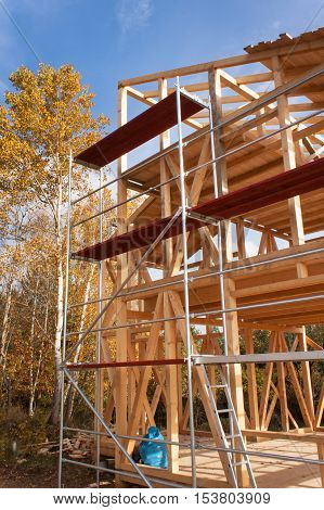 Metal scaffolding around the unfinished house. Construction of ecological house. Wooden frame of house under construction.Framed New Construction of a House. Timber house in building process