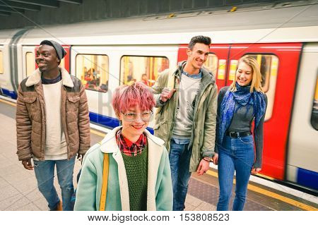 Multiracial group of hipster friends having fun in tube subway station - Urban friendship concept with young people walking together in city underground area - Vivid color with focus on pink hair girl