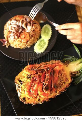 Freshly prepared pineapple fried rice with seafood - prawn squid octopus served inside of a pineapple carved like a bowl.