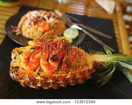 Freshly prepared pineapple fried rice with seafood - prawn squid octopus served inside of a pineapple carved like a bowl.