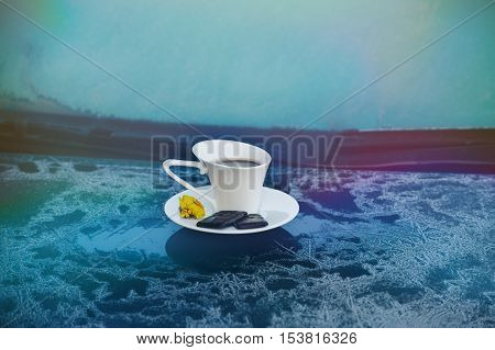 Hot strong Cup of coffee with chocolate on the frozen hood of the blue car. Morning, cold, frost, hoarfrost, waiting