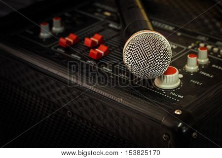 Microphone in soft focus placing on audio synthesiser electronic music instrument sound mixer machine in blur meeting room: Metallic material mic for vocal entertainment in seminar auditorium hall