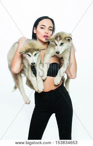pretty sexy brunette woman with long straight hair fashion makeup in black bra holding cute little dogs of husky isolated on white background