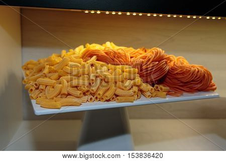Uncooked Penne Italian Pasta And Red Spaghetti Shown On White Dish