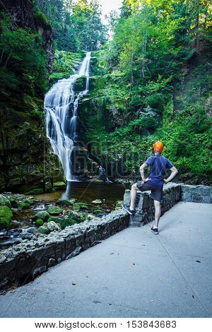 Man in helmet look at Kamienczyk Waterfall from observation deck.