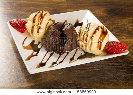 Petit Gateau Dessert With Ice Cream And Strawberry On Wooden Background