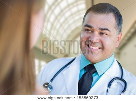 Hispanic Male Doctor or Nurse Talking With a Patient Inside Hospital Offices.