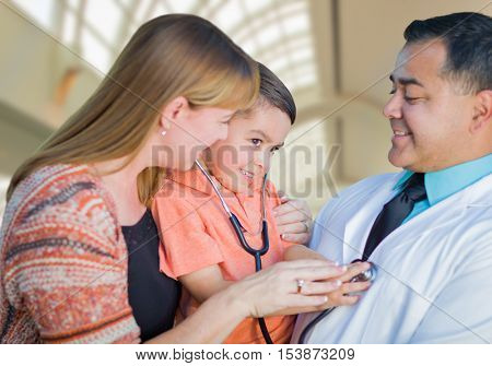 Happy Mixed Race Boy, Mother and Hispanic Doctor Having Fun With Stethoscope Inside Hospital Offices.