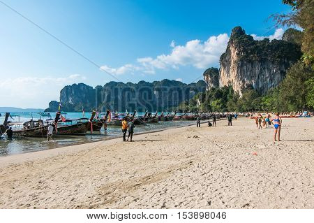 KRABI - JANUARY 20, 2015 : Tourist enjoying a beach walk on a sunny day JANUARY 20, 2015 at Railay Beach in Krabi, Thailand. Railay Beach is a small peninsula with white sand beaches, soaring limestone cliffs, viewpoints, caves and a lagoon hidden inside 