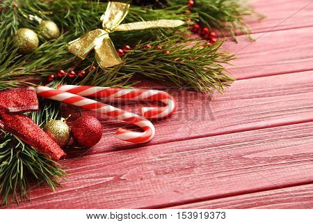 Christmax Tree Branch With Baubles, Candies On Red Wooden Table