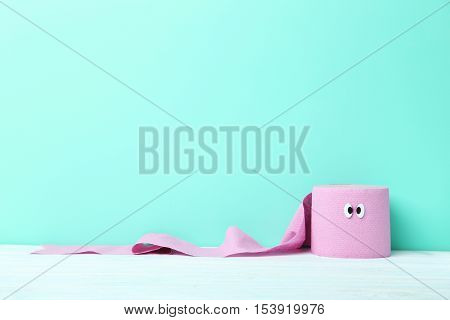 Toilet paper with googly eyes on green background
