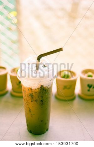 Iced coffee with straw in plastic cup with cuctus backgroundcross process picture style.