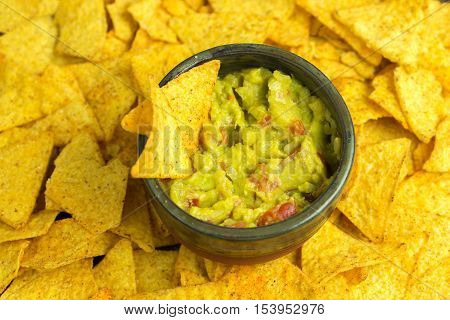 Guacamole in home crafted bowl with tortilla chips and around.