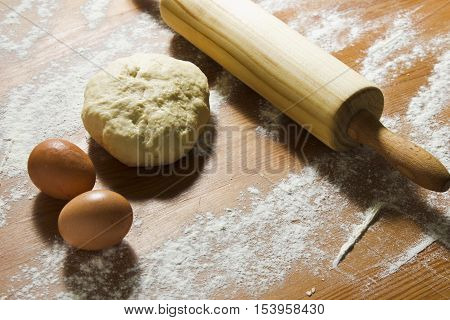 Eggs rolling pin and dough on the wooden table in the kitchen. Ingredients and tools for baking dough. Still life in a rustic style. Easter preparation.