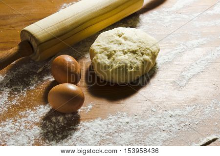Eggs rolling pin and dough on the wooden table in the kitchen. Ingredients and tools for baking dough. Still life in a rustic style. Easter preparation.
