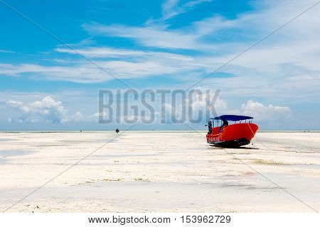 Red boat on the beach of Zanzibar on the blue sky background.
