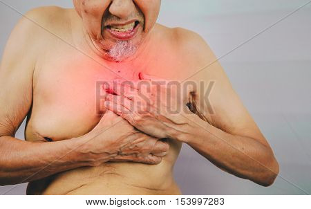 acute pain possible heart attack senior man is clutching he chest.