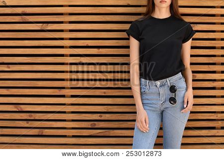 Young Woman Wearing Black T-shirt Against Wooden Wall On Street. Urban Style