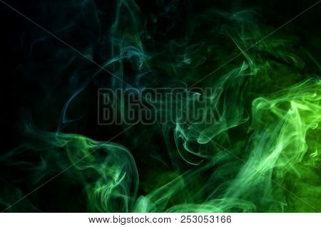 Cloud Of Blue And Green Smoke On A Black Isolated Background. Background From The Smoke Of Vape