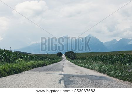 Empty Countryside Road To The Mountain Through Summer Fields