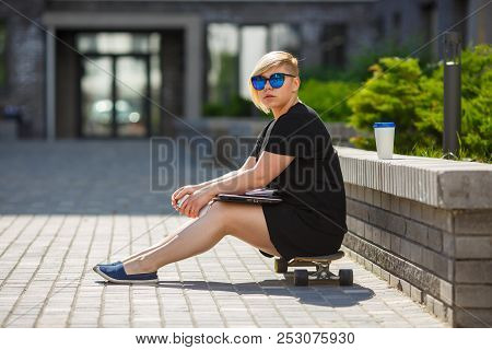 Girl Young Student Plus Size In Sunglasses Sitting On Skateboard, In Hands Phone, Laptop, Glass Of C