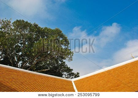 Orange Roof Of Thai Temple In Sunny Day Contrasts With Bright Blue Sky