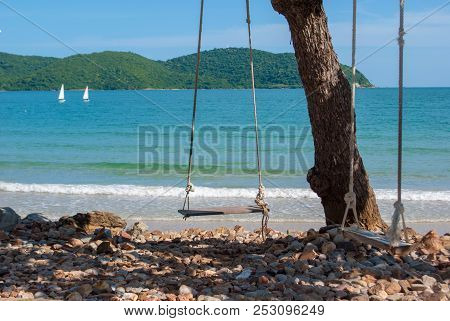 Lonely Wooden Swings In Front Of The Blue Sea