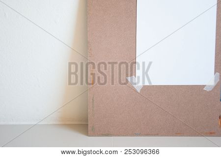 Watercolor Painting Board With Attached Art Paper Leaning On Cement Wall Having Light From Right Sid