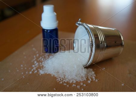 Natural Salt In Silvery Bucket And Blue Etherial Oil Bottle On Weathered Wooden Table