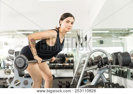 Determined Athlete Doing Bent Over Row Exercise With Barbell In Gym