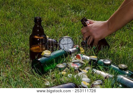 Open Bottles Of Beer And Beer Sponges Scattered On A Green Lawn On A Hot Summer Day.