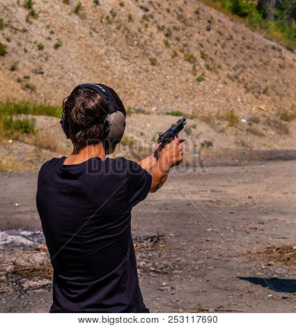 A Young Man Concentrates As He Fires His Pistol. The Smoke From The Gun Powder, The Recoil Of The .4