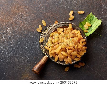 Heap Of Yellow Raisins. Top View Of Dried Grapes With Green Leaf.