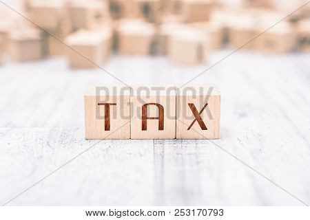 The Word Tax Formed By Wooden Blocks On A White Table, Reminder Concept