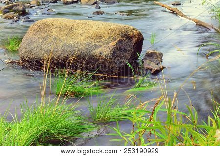 Ransparent Cold Water Of A River Flows Between Picturesque Summer Stones Against A Background Of Gre