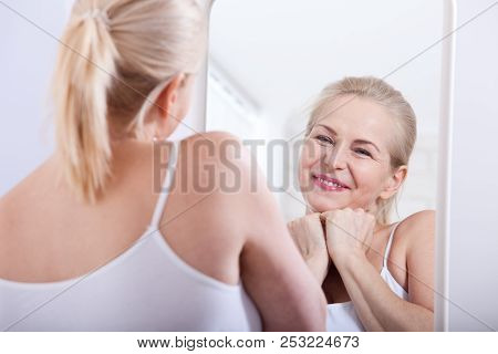 Forty Years Old Woman Looking At Wrinkles In Mirror. Plastic Surgery And Collagen Injections. Makeup